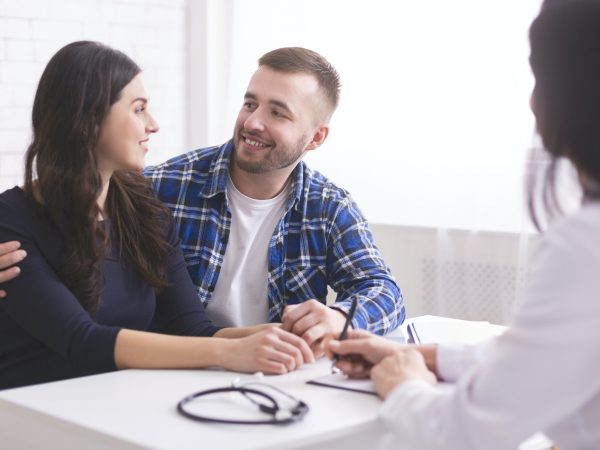 Young couple smiling at each other, happy to hear doctor's news